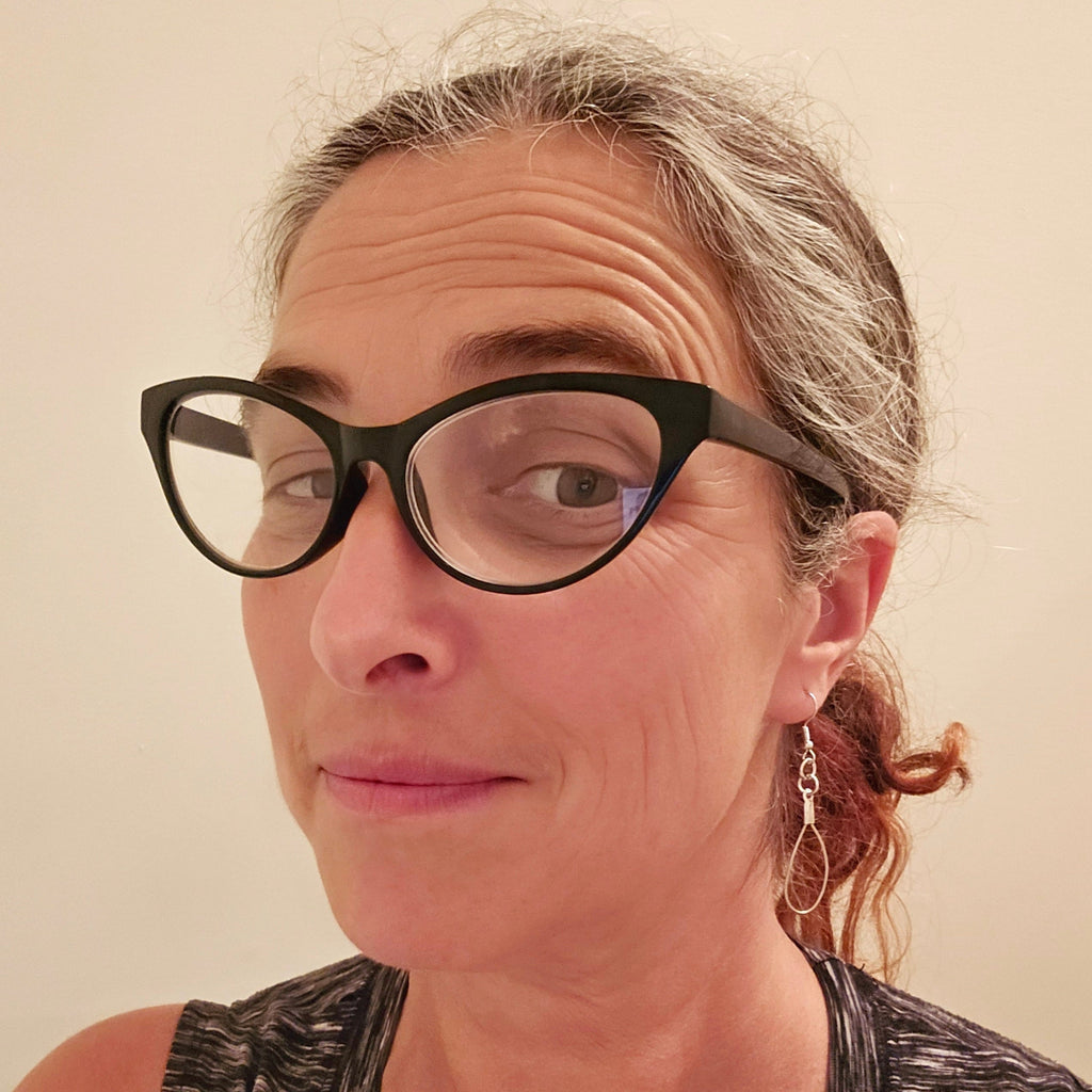 woman in glasses wearing a pair of teardrop style earrings made from upcycled violin strings 