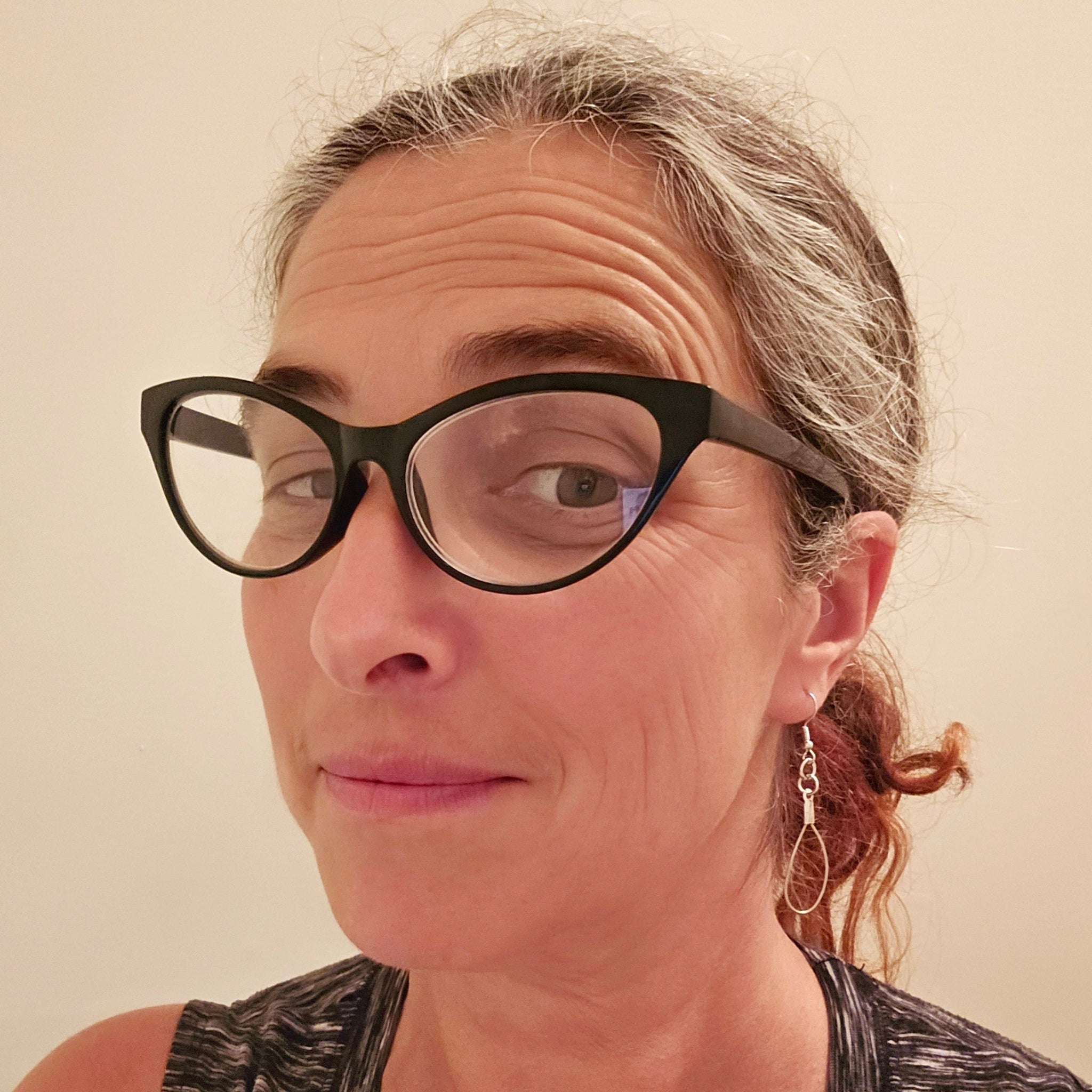 woman in glasses wearing a pair of teardrop style earrings made from upcycled violin strings 