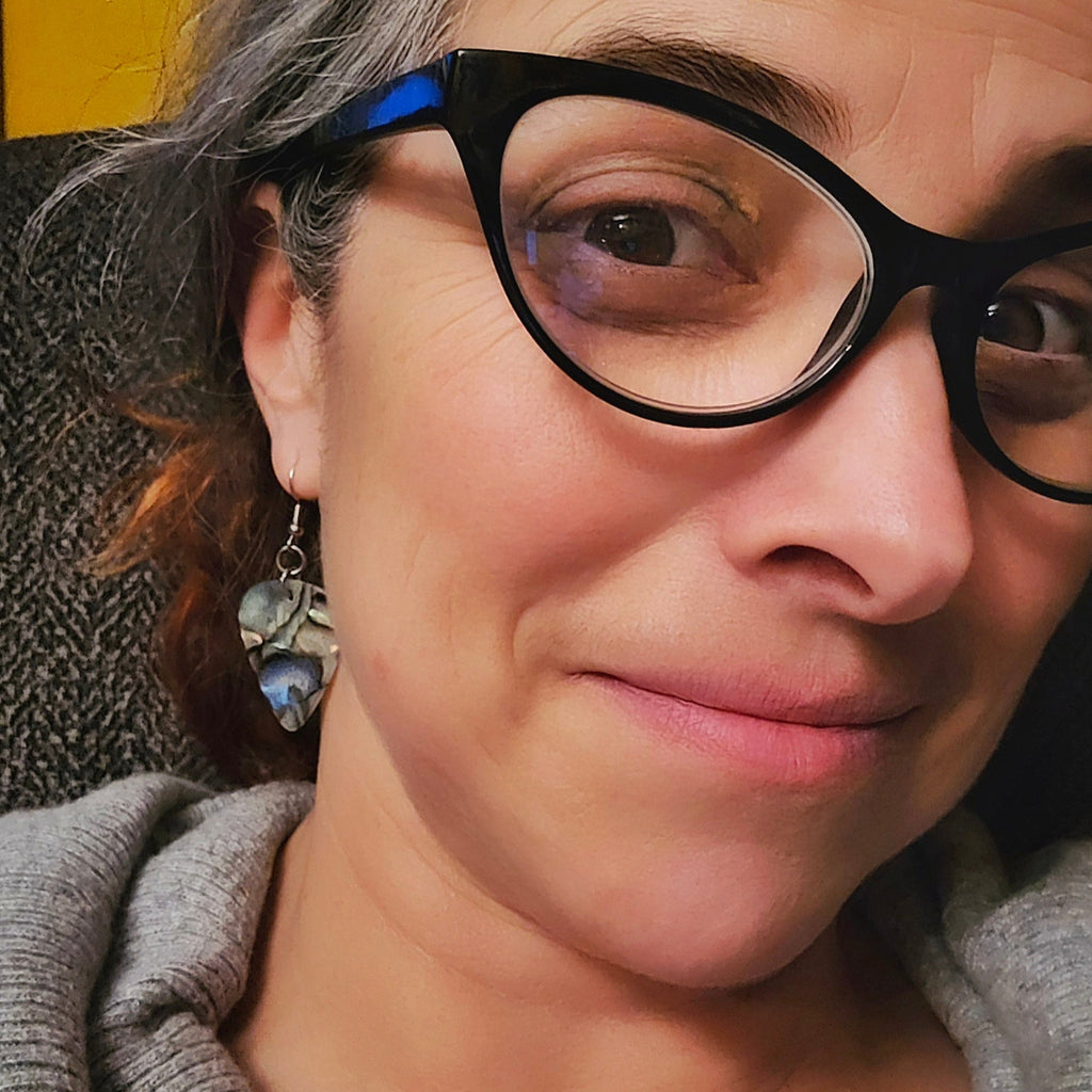 Woman with glasses wearing guitar pick earrings 