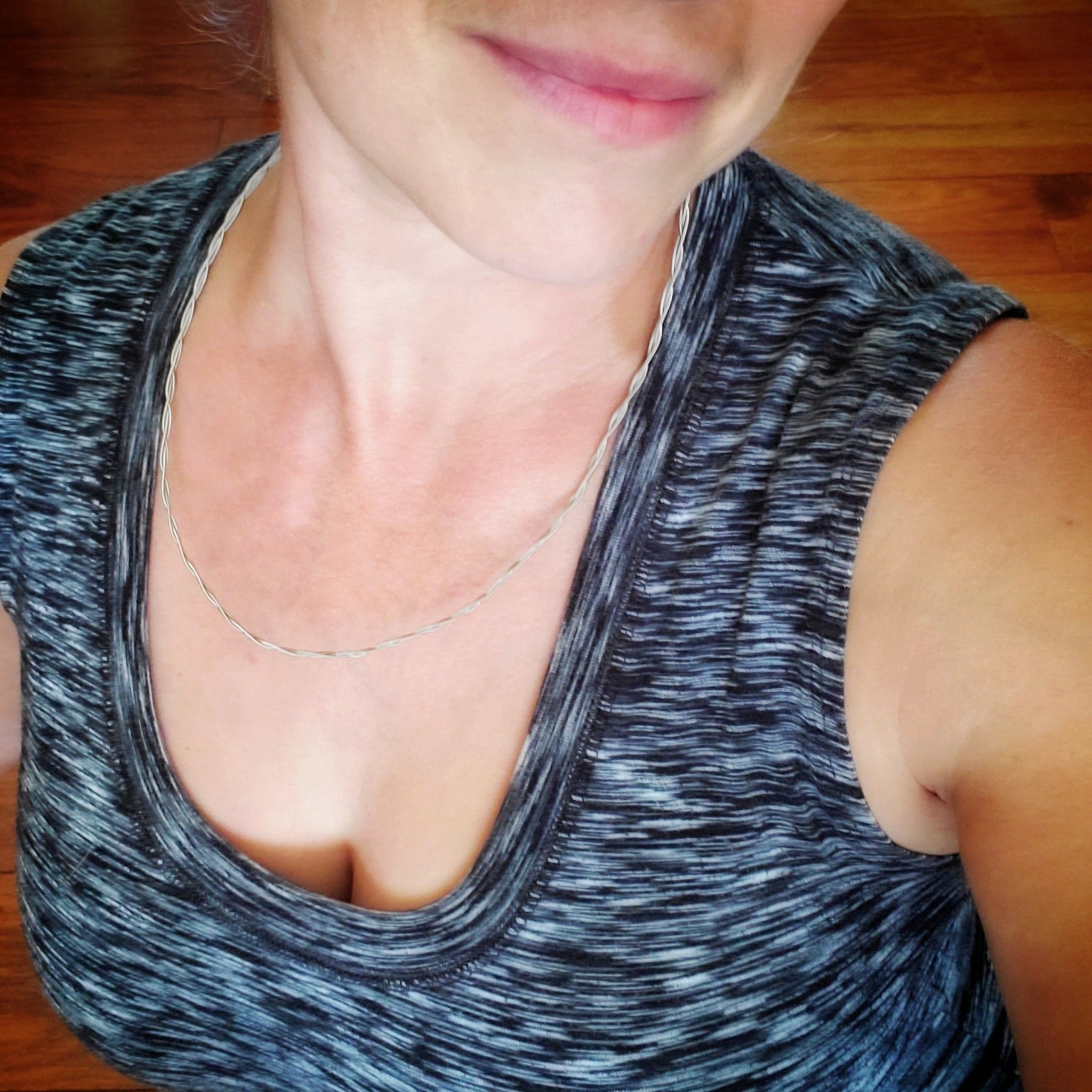 a woman's head and neck, she is wearing a silver chain made from braided guitar strings