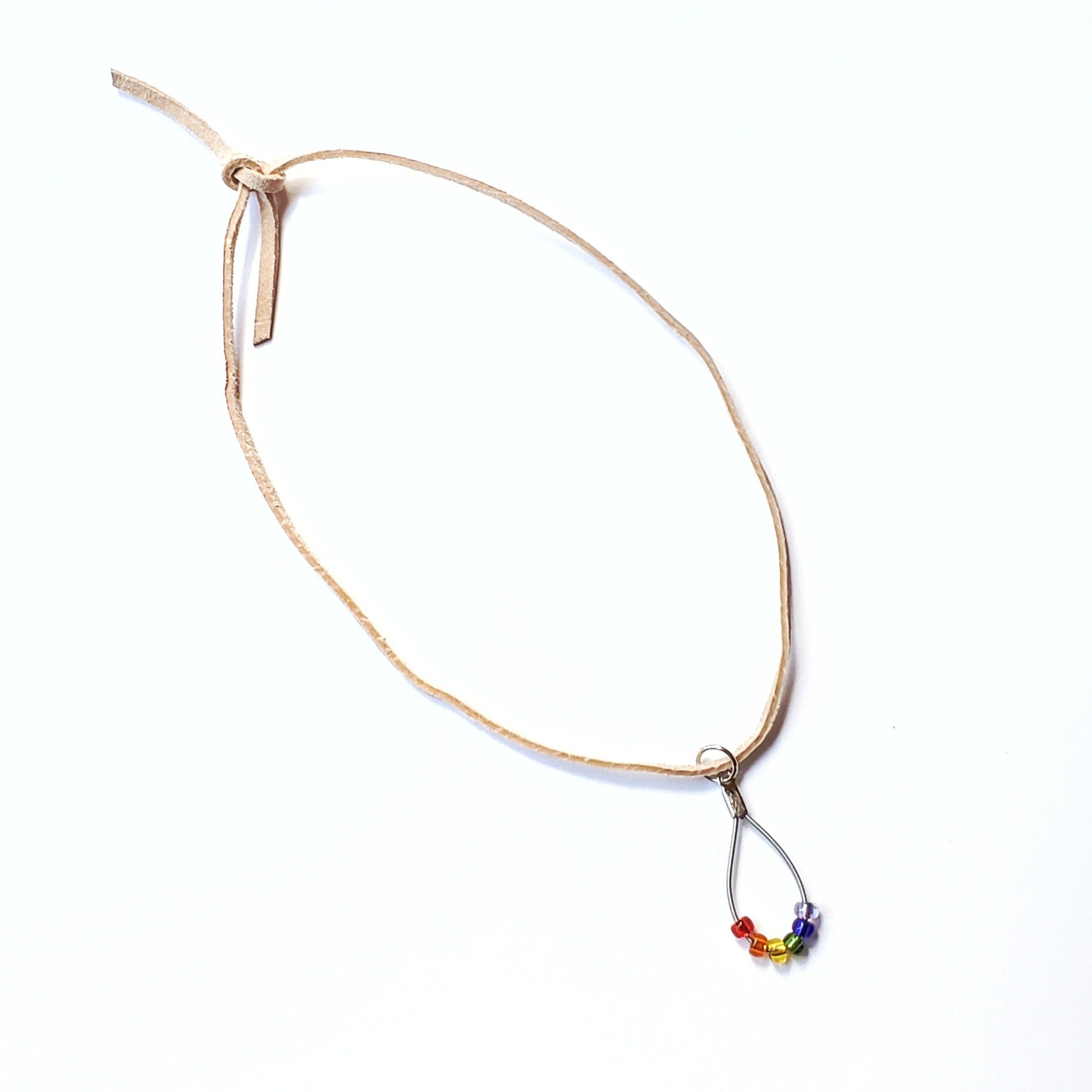 necklace made from an upcycled guitar string - 6 glass beads represent the colours of the LGBTQ flag (red, orange, yellow, green, blue and purple) and a beige suede cord - white background