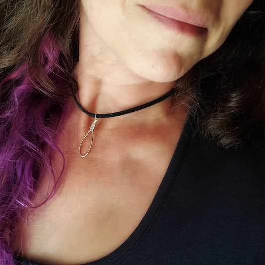 a woman's partially seen face and neck- long brown and purple curly hair - on her neck she is wearing a necklace - the silver coloured teardrop pendant is made from an upcycled cello string which hangs on a black genuine leather cord