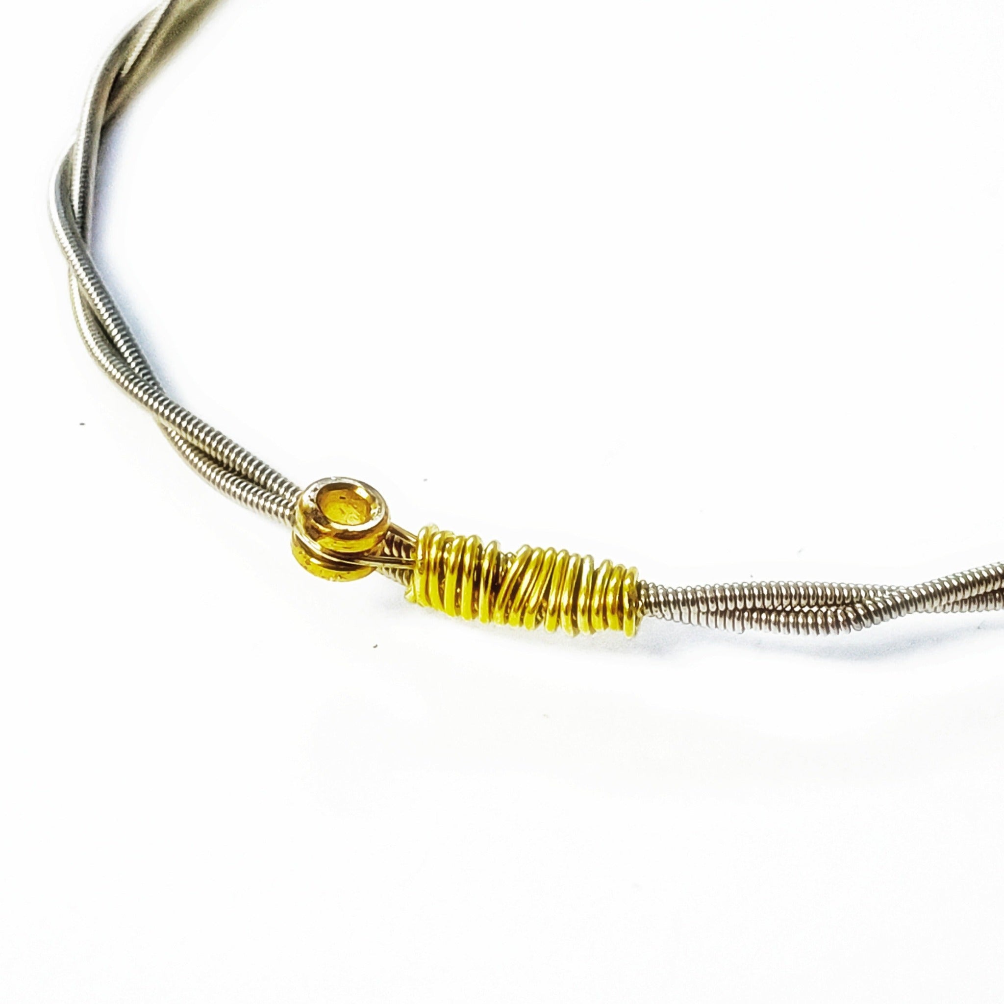close-up of a bangle style bracelet made from an upcycled guitar string - white background