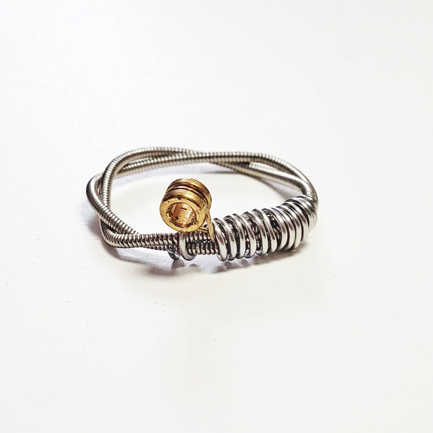 a silver coloured guitar string ring - white background
