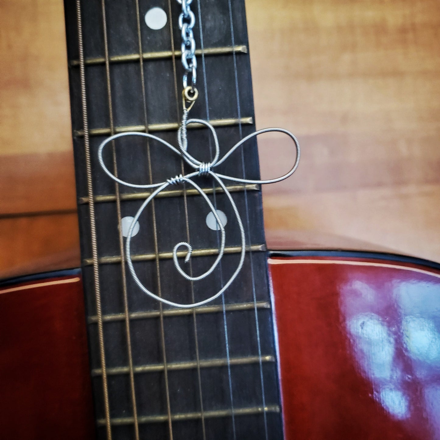 rearview mirror  decoration shaped like an angel made from an upcycled guitar string on the neck of a red guitar