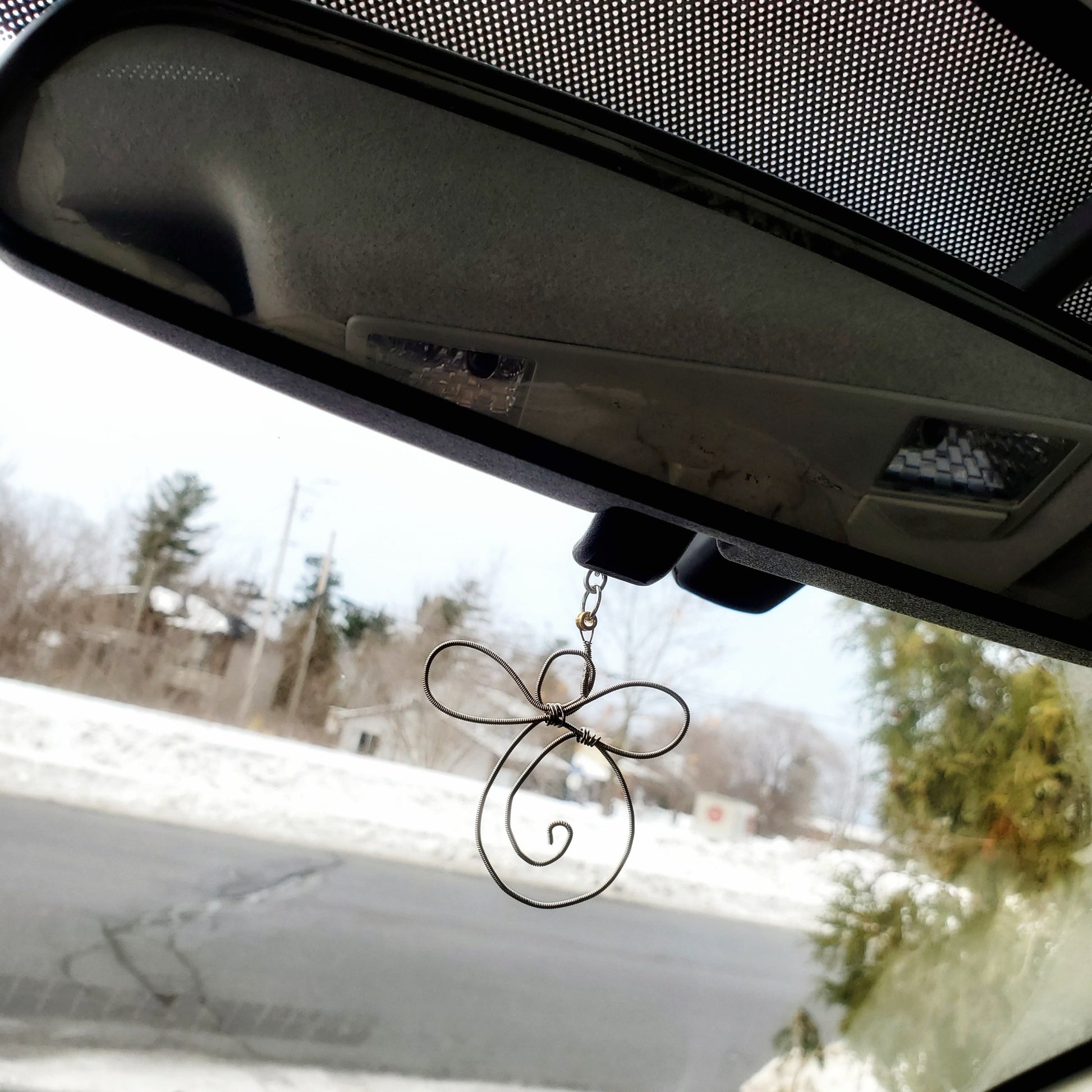 rearview mirror  under which is a decoration shaped like an angel made from an upcycled guitar string