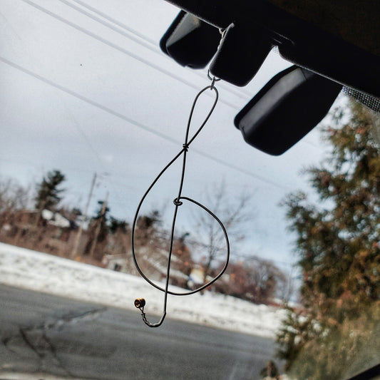 rearview mirror on which there is a decoration in the shape of a treble clef, made from an upcycled guitar string