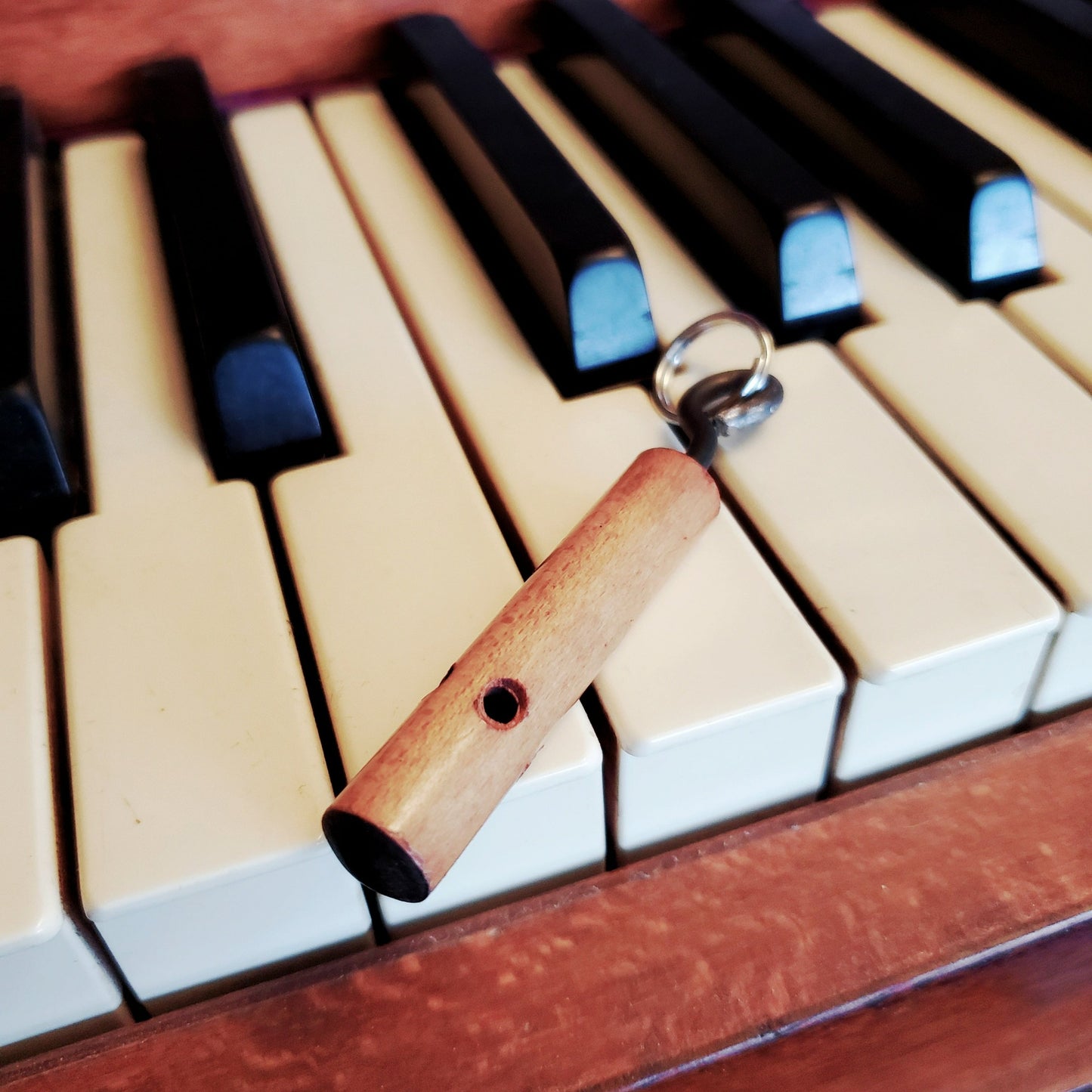 keychain made from part of a piano key - lying on top of a piano keyboard