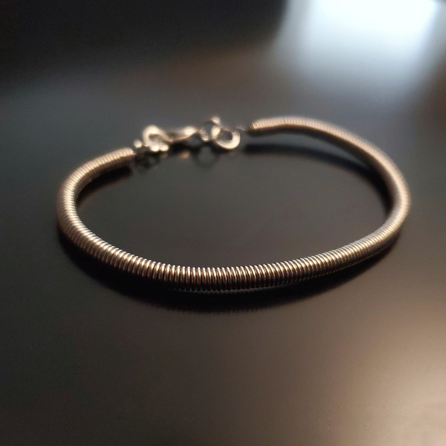 silver coloured clasp style bracelet made from an upcycled electric bass guitar string