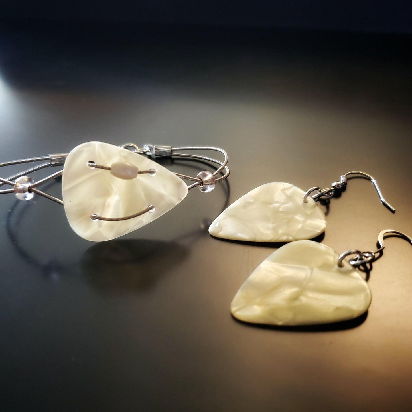jewelry set - bracelet is made from upcycled guitar strings and a beautiful pearly off-white guitar pick. The earrings are made from matching plectrums (guitar picks)