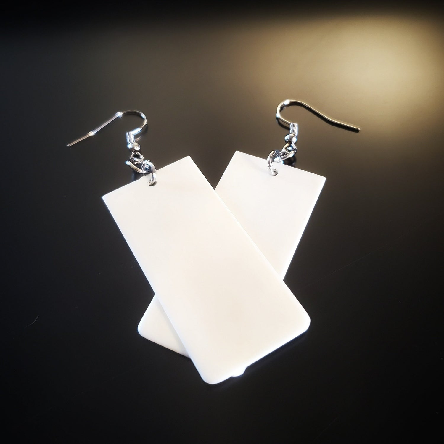 a pair of earrings made from upcycled ivory piano key toppers 