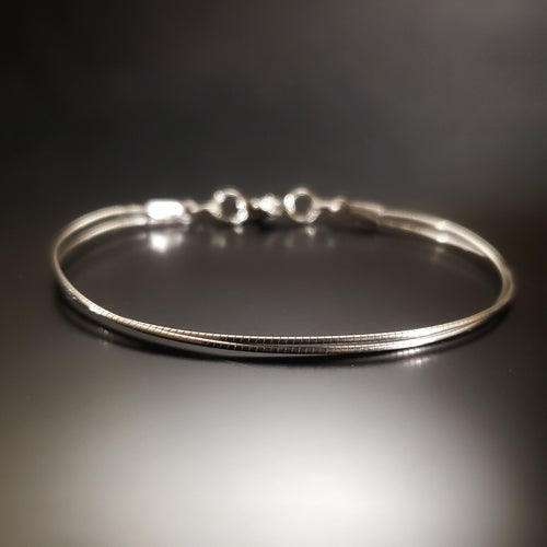 bracelet de couleur argent fabriqué à partir d'une corde de violoncelle recyclée - fond noir et gris