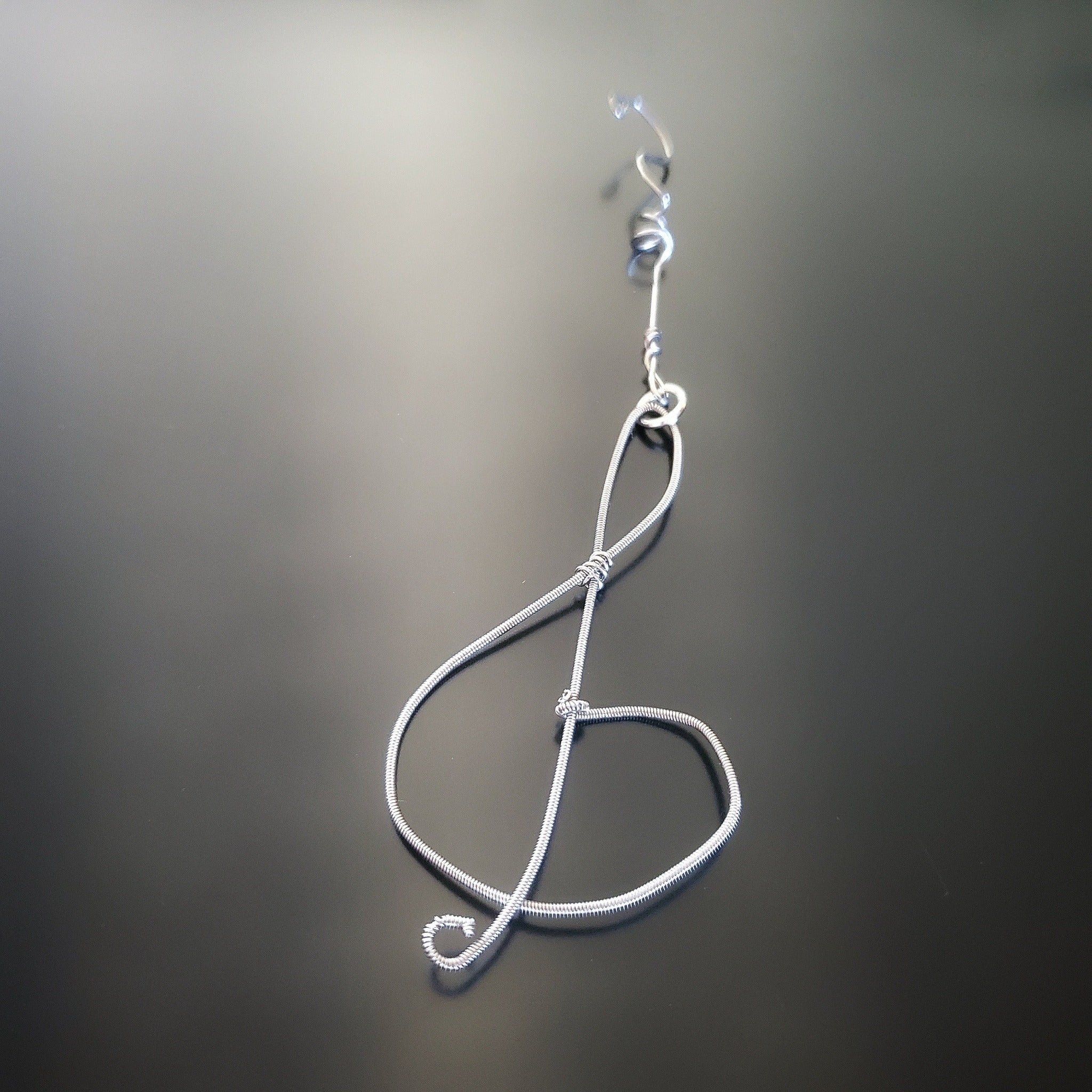 Christmas ornament in the shape of a treble clef, made from an upcycled guitar string
