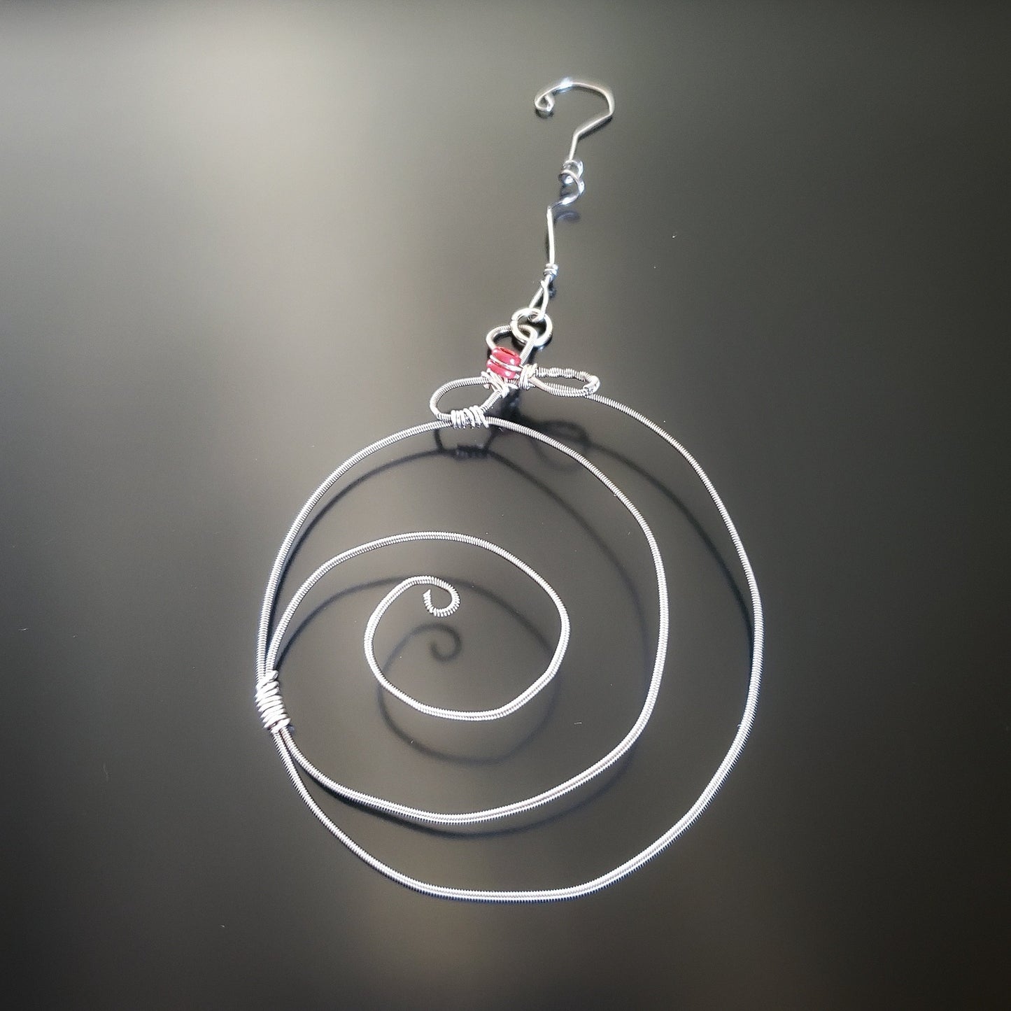 Christmas ornament in the shape of a round swirl made from an upcycled guitar string