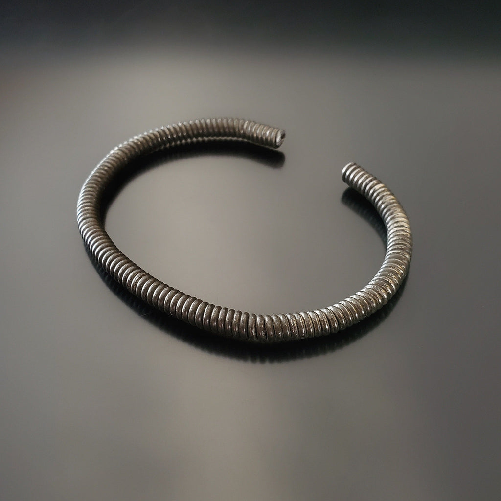 charcoal grey cuff style bracelet made from an upcycled piano string