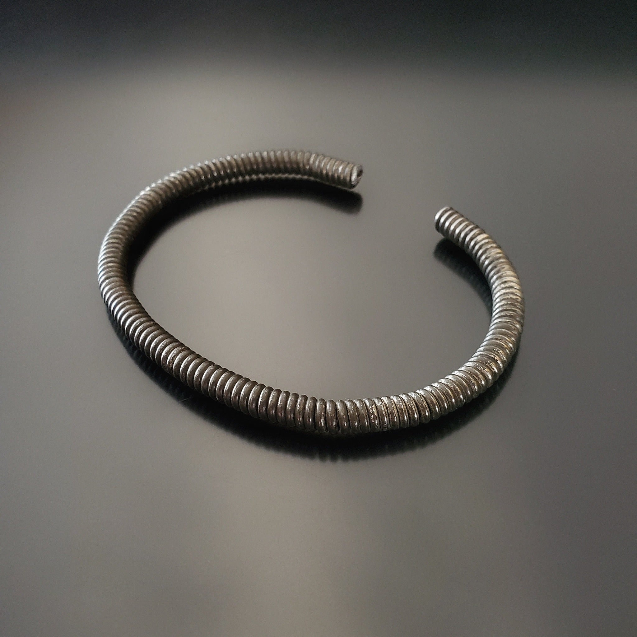 charcoal grey cuff style bracelet made from an upcycled piano string