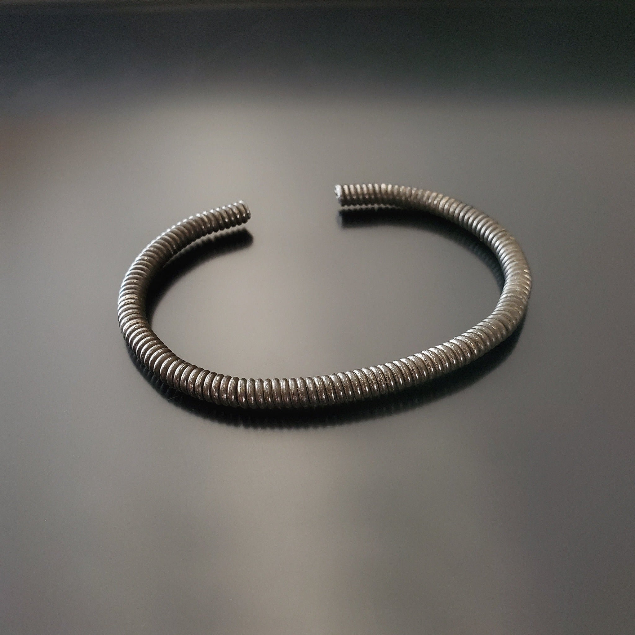 charcoal grey cuff style bracelet made from an upcycled piano string