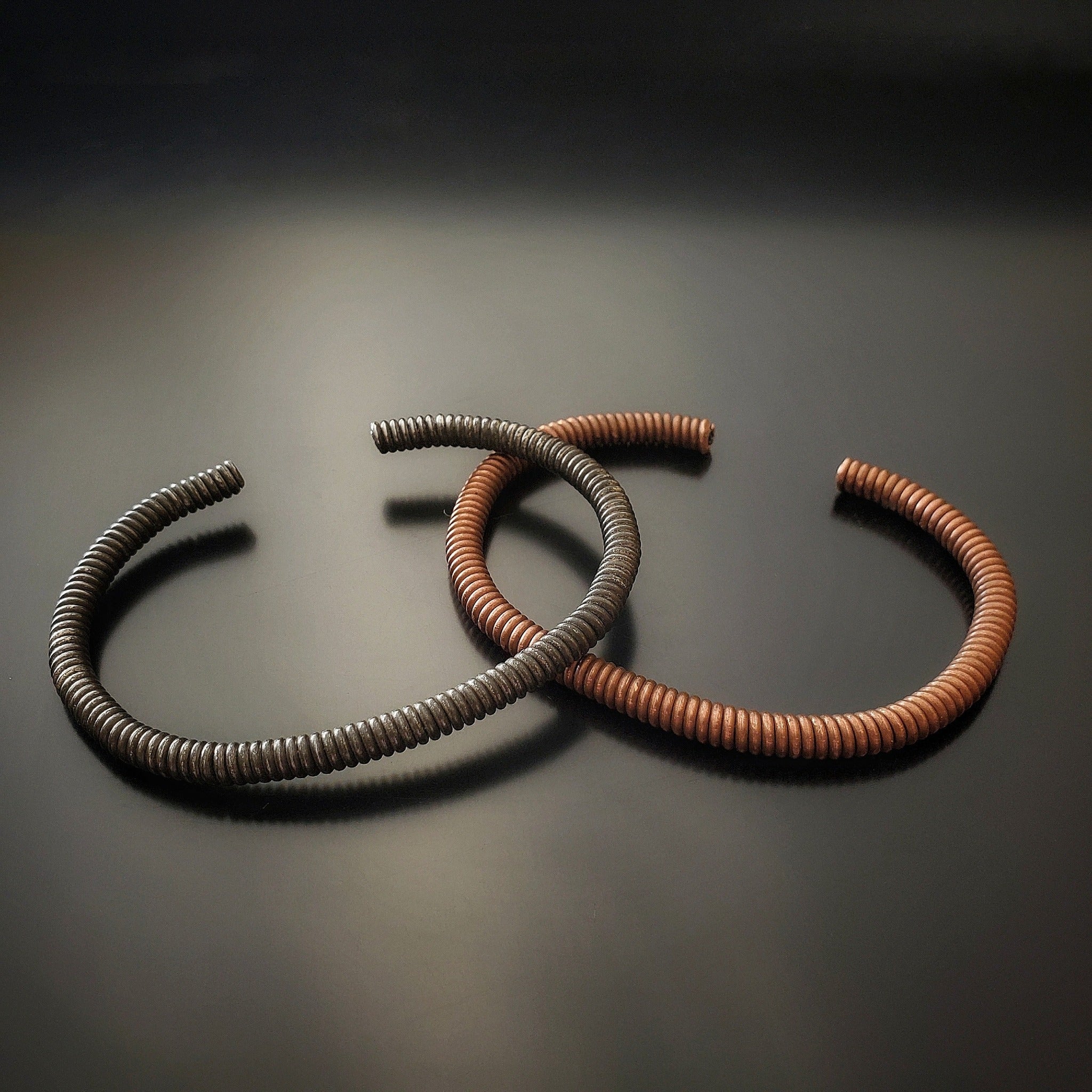 copper and charcoal grey cuff style bracelets made from an upcycled piano strings