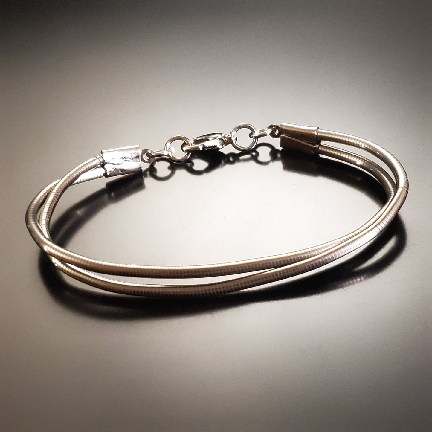 silver coloured clasp style bracelet made from upcycled upright bass strings