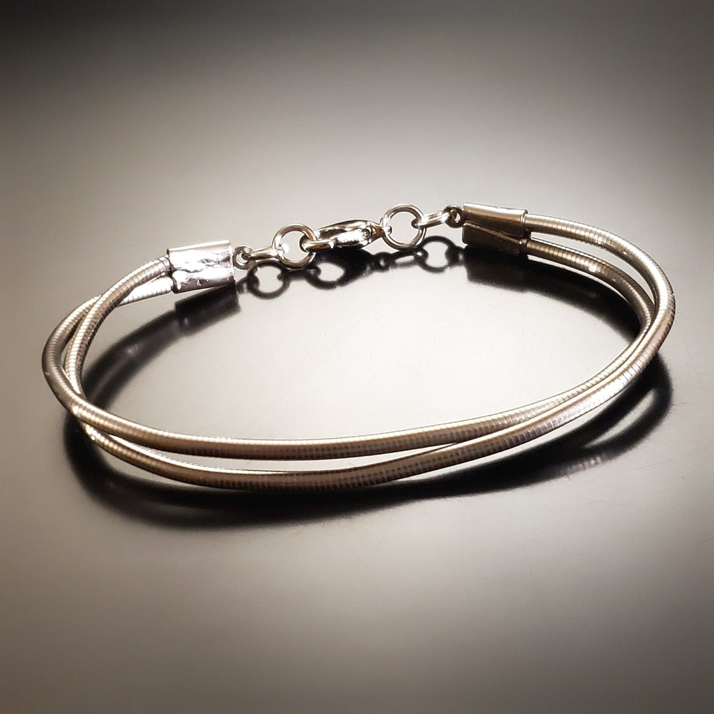 silver coloured clasp style bracelet made from upcycled upright bass strings