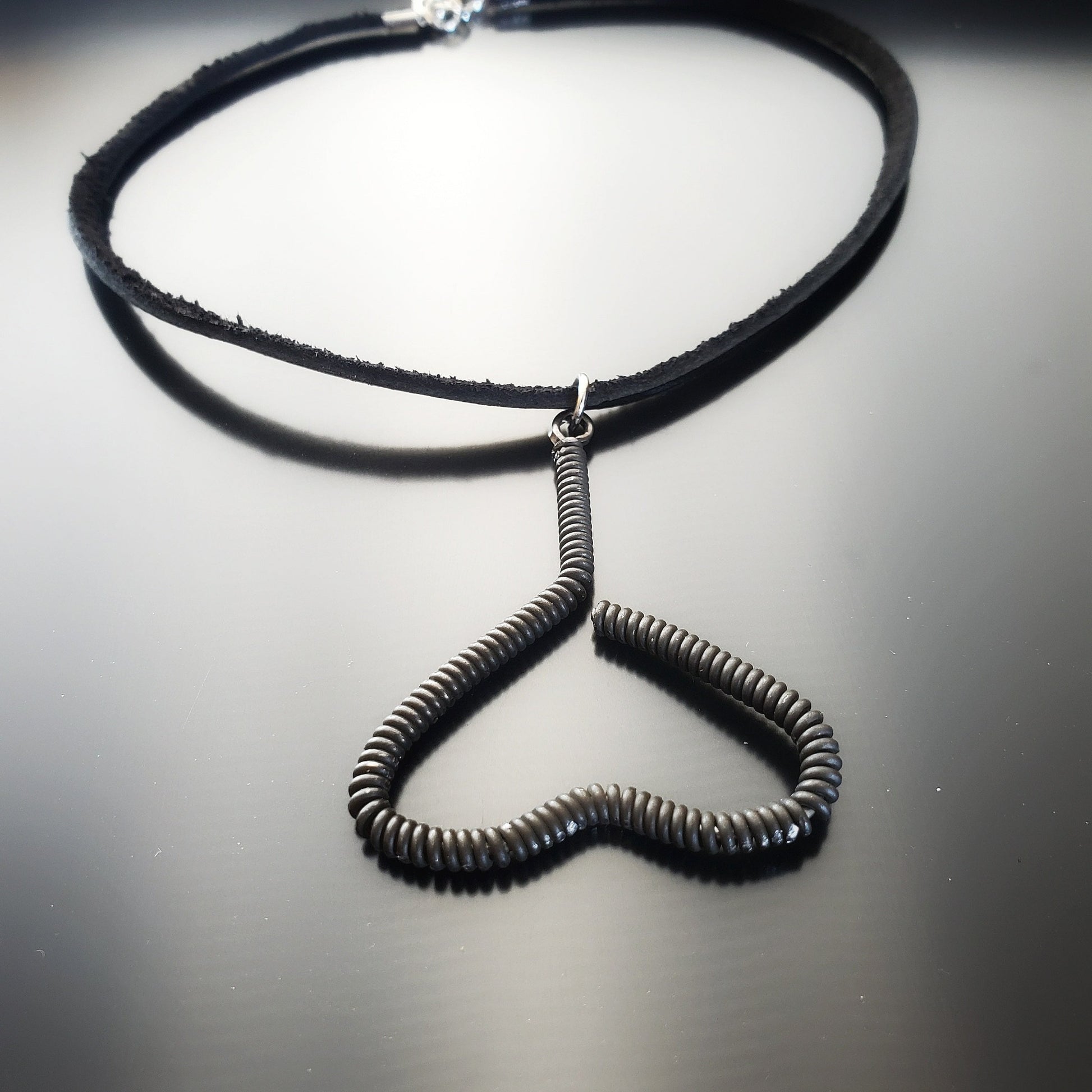 necklace - pendant is in the shape of an upside down heart and is made from a black upcycled piano string - pendant hangs off a black leather cord