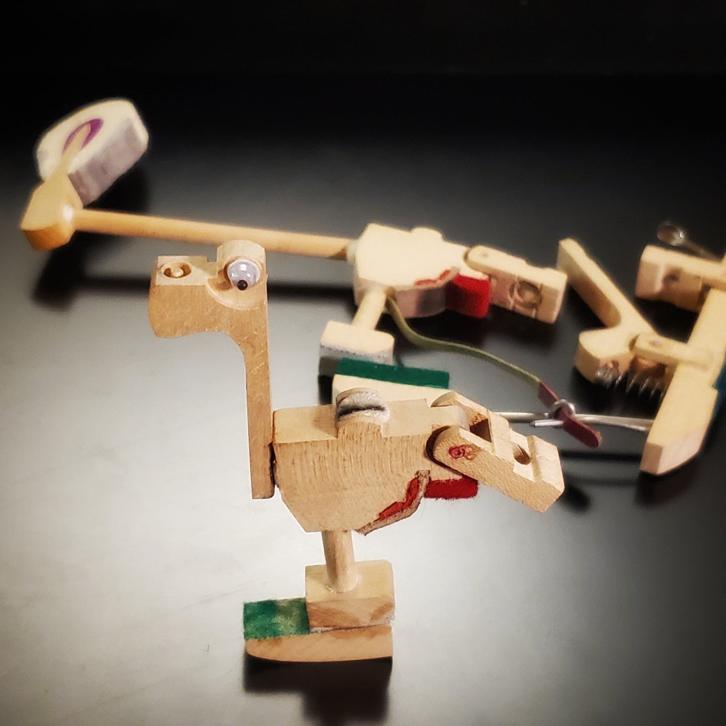 a magnet in the shape of a dinosaur-like animal made from pieces of a piano mechanism - behind it are pieces of a piano mechanism  like those from which it was made