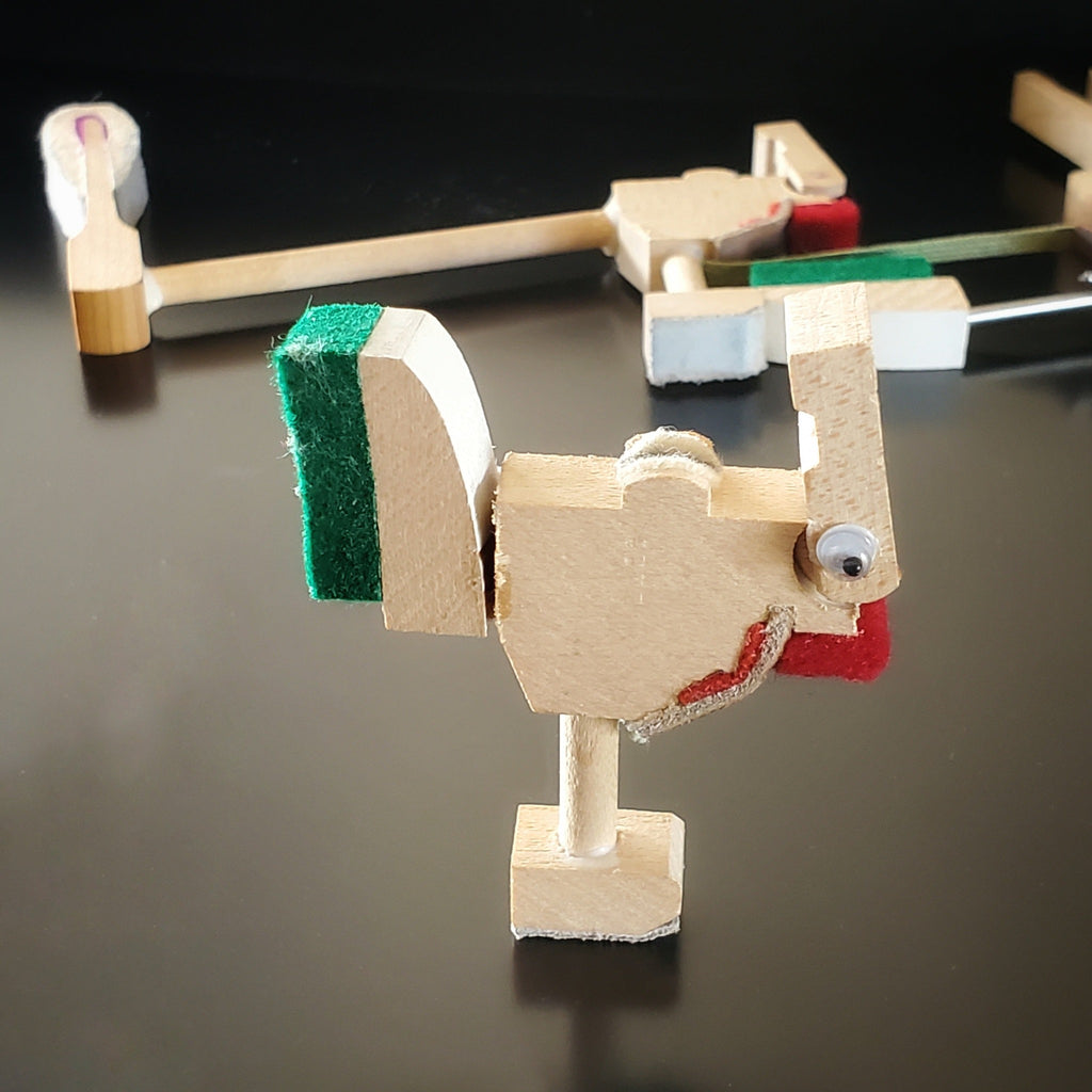 a magnet in the shape of a chicken made from pieces of a piano mechanism - behind it a pieces of piano mechanism like those used to make it