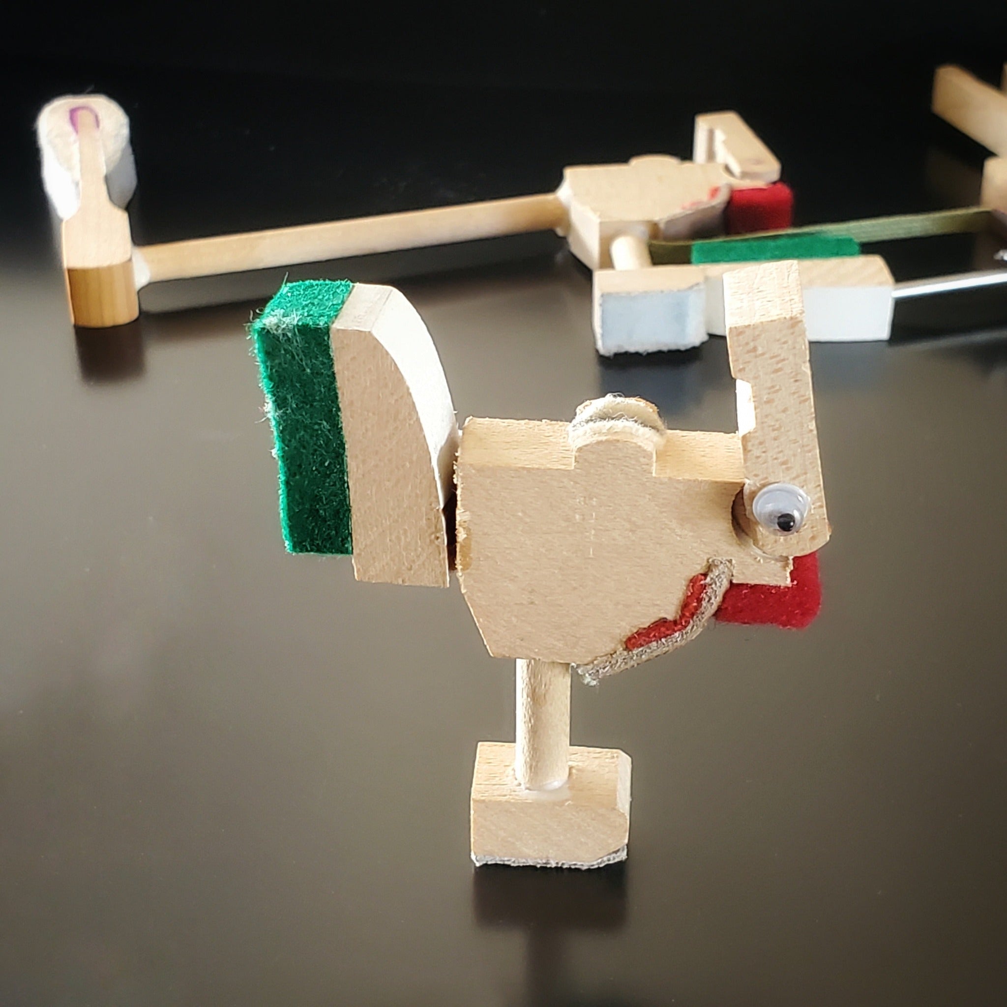 a magnet in the shape of a chicken made from pieces of a piano mechanism - behind it a pieces of piano mechanism like those used to make it