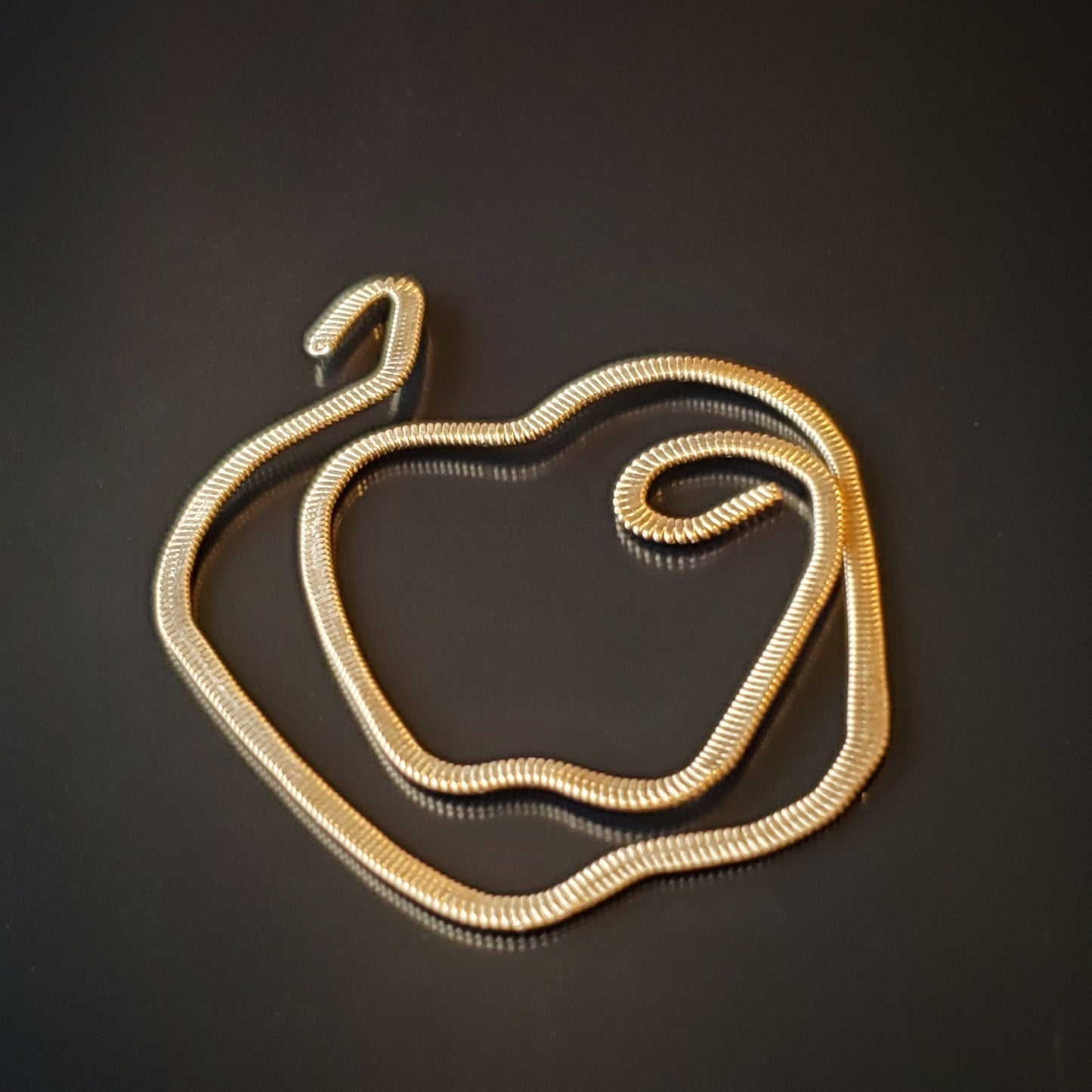 gold guitar string bookmark shaped like an apple on a black background