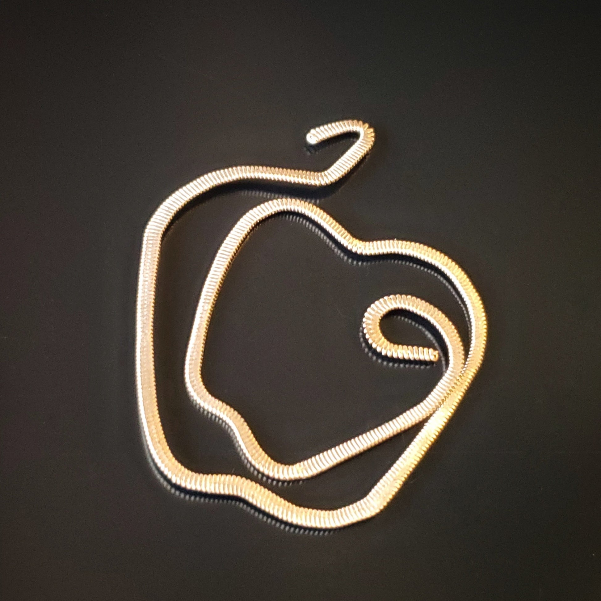 gold guitar string bookmark shaped like an apple on a black background
