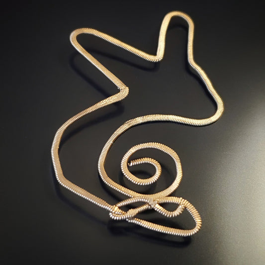 a gold coloured bookmark in the shape of a bunny - the bookmark is made from an upcycled guitar string hammered flat - black background