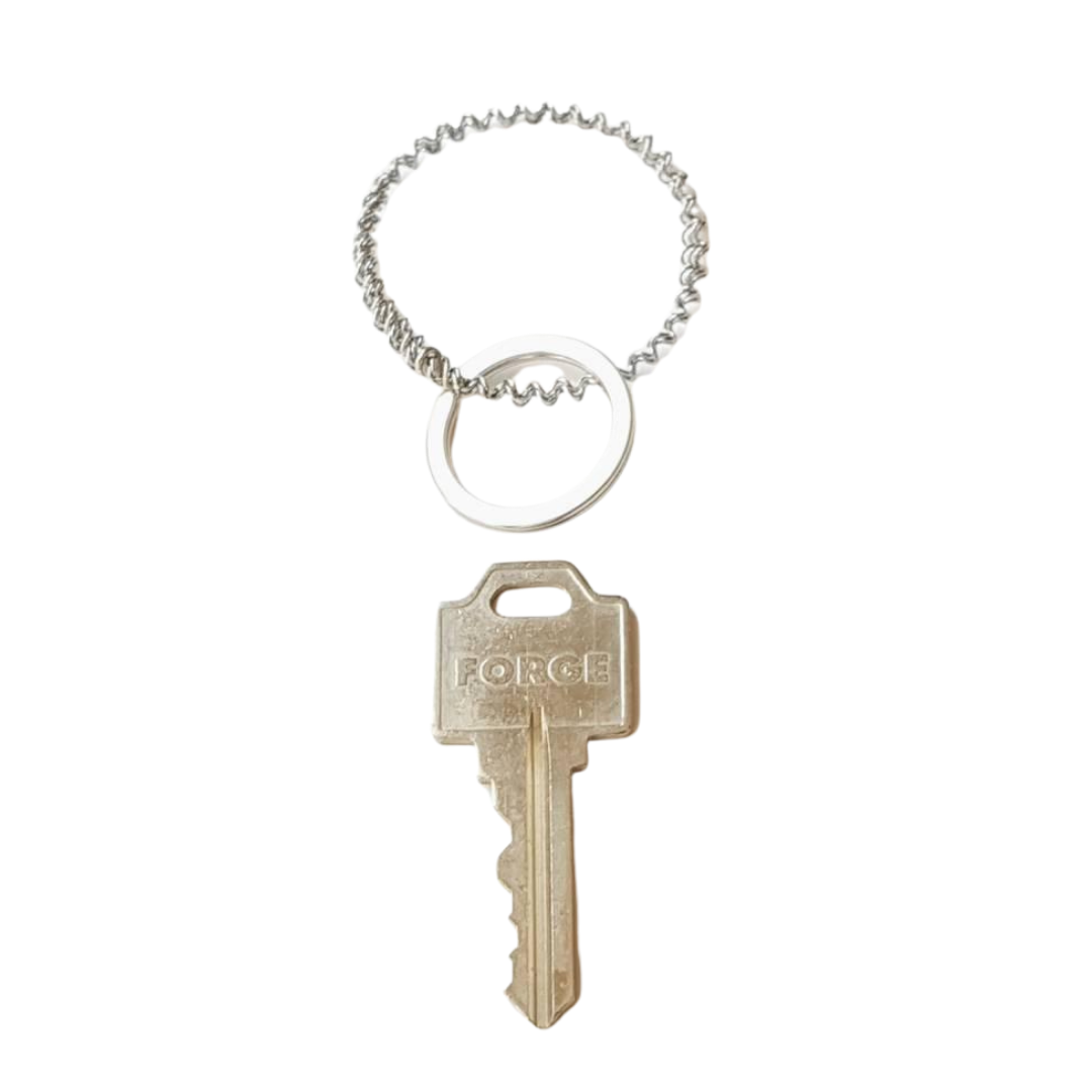 a keychain made from an upcycled snare drum string is above a silver key - white background