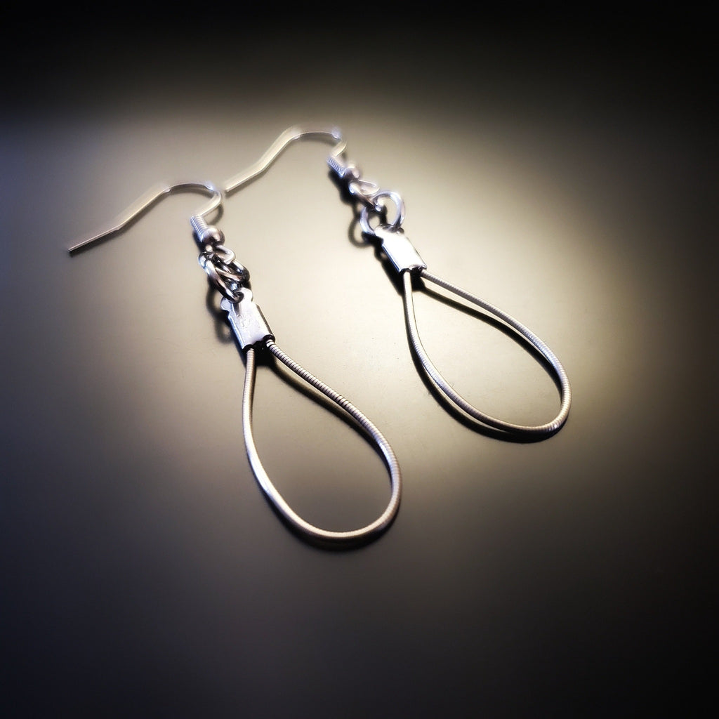 a pair of teardrop style earrings made from upcycled violin strings on black background