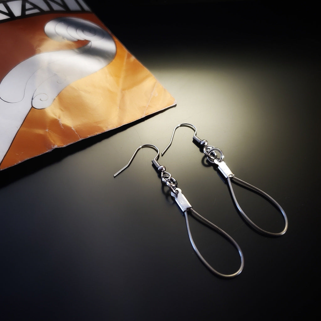 a pair of teardrop style earrings made from upcycled violin strings - top left is a piece of paper with an image of a violin neck on a yellow background