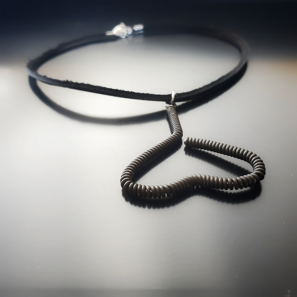 necklace - pendant is in the shape of an upside down heart and is made from a black upcycled piano string - pendant hangs off a black leather cord