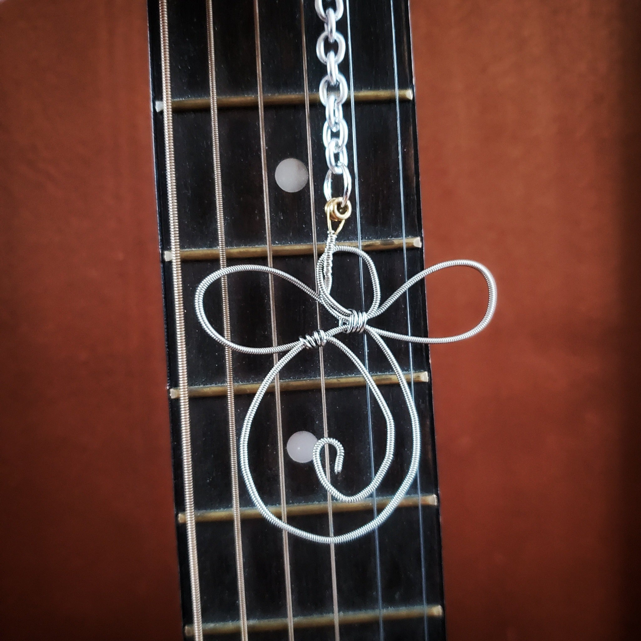 rearview mirror decoration shaped like an angel made from an upcycled guitar string on the neck of a red guitar