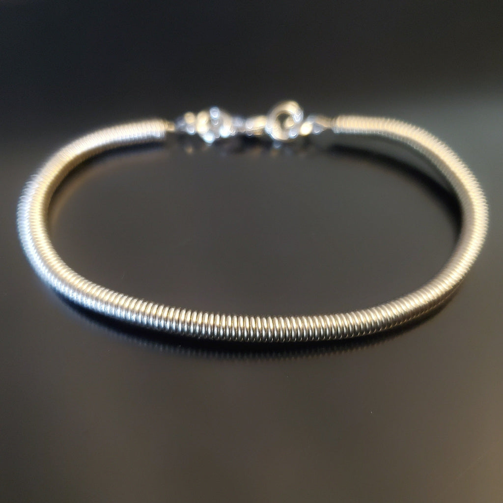 silver coloured clasp style bracelet made from an upcycled electric bass guitar string