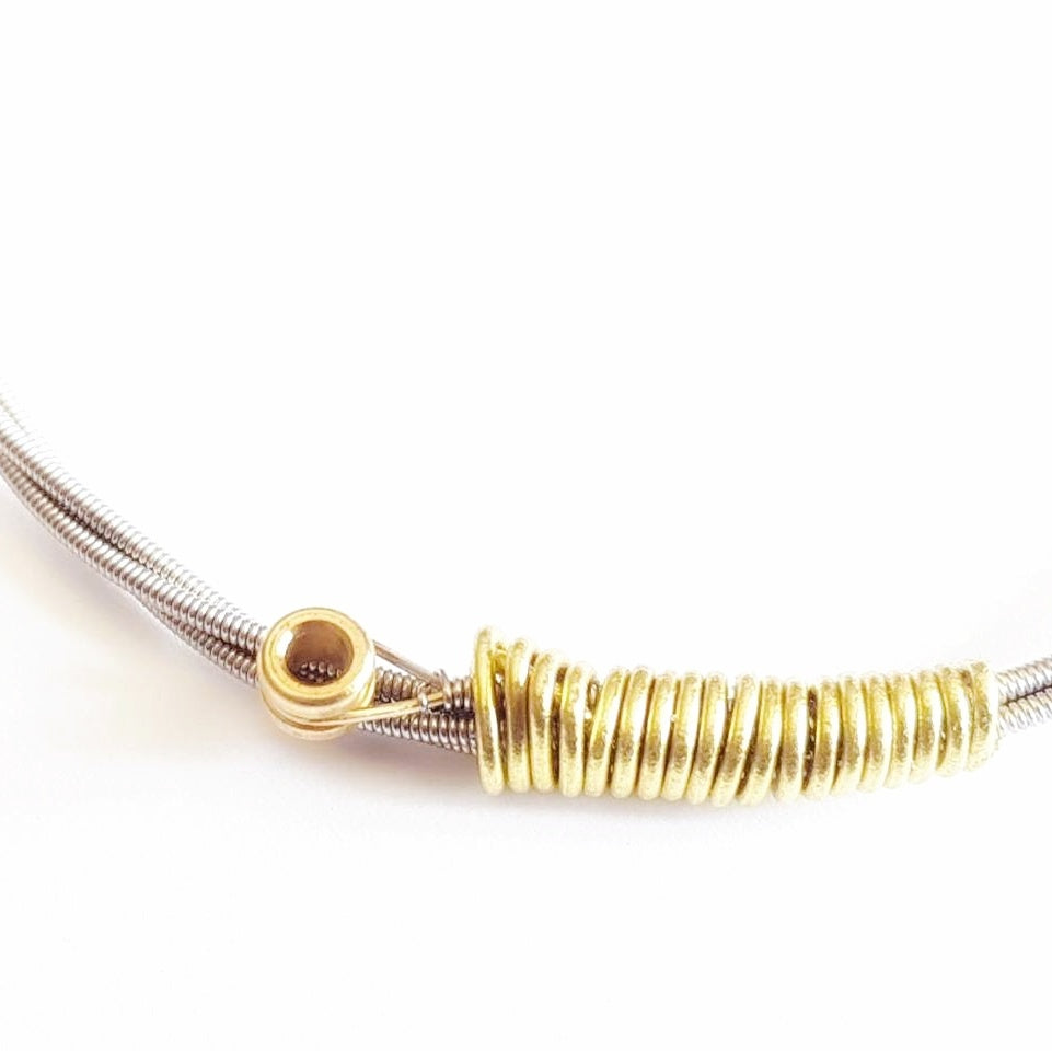 close-up of a bangle style bracelet made from an upcycled guitar string - white background