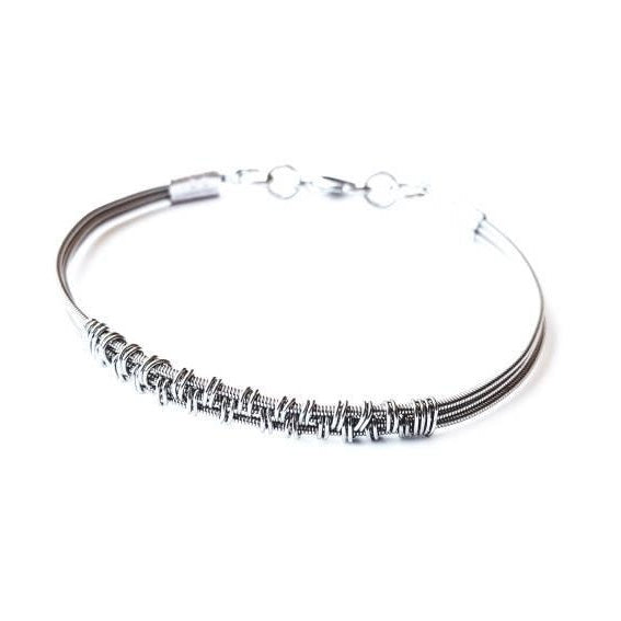 silver coloured clasp style bracelet made from 3 upcycled guitar strings - there is wire wrapped around the center of the bracelet in a pattern - white background