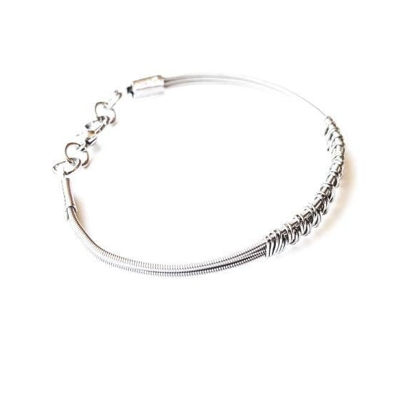 silver coloured clasp style bracelet made from 3 upcycled guitar strings - there is wire wrapped around the center of the bracelet in a pattern