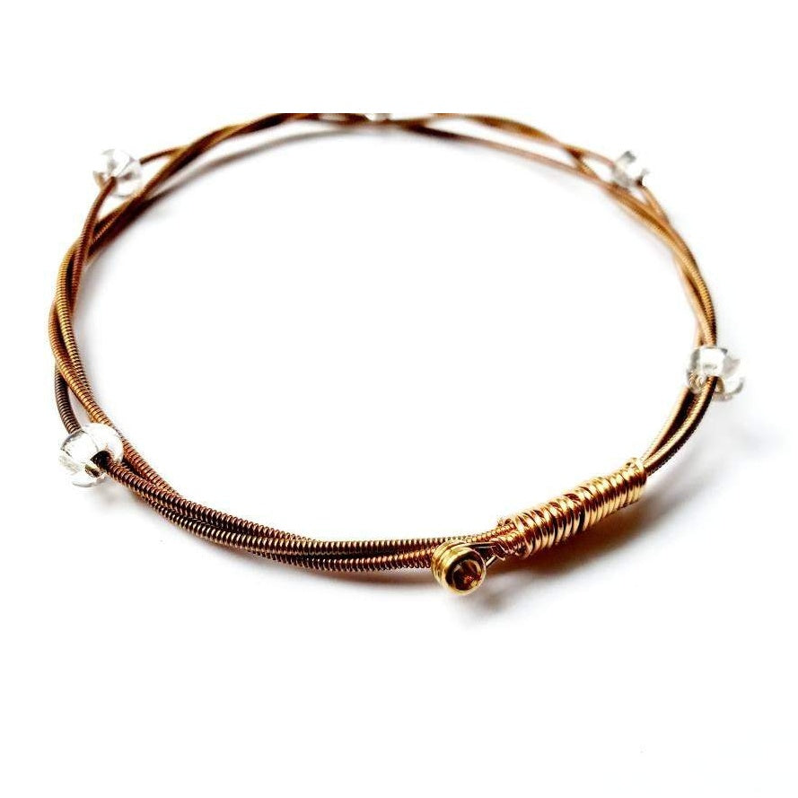copper coloured bangle style bracelet made from an upcycled guitar string and clear glass beads - white background