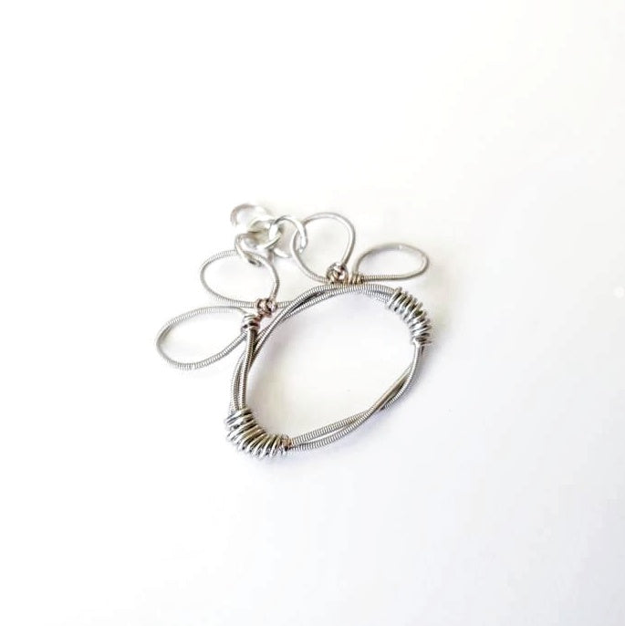 paw print pendant made from an upcycled guitar string - white background