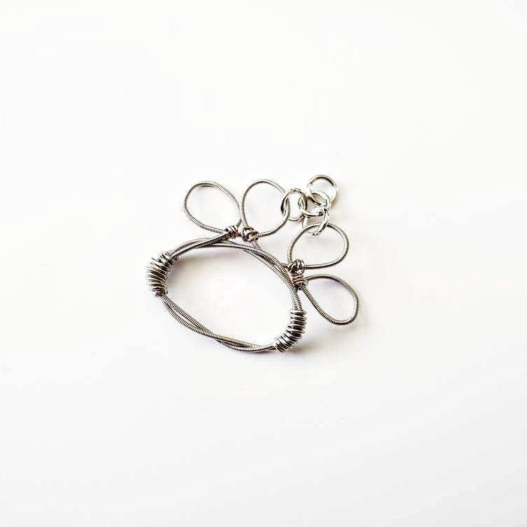 paw print pendant made from an upcycled guitar string - white background