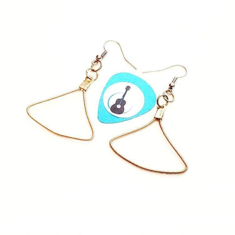 a pair of gold coloured earring made from an upcycled guitar string in the shape of a triangle in the middle of the pair is a blue guitar pick with an image of a black guitar - white background