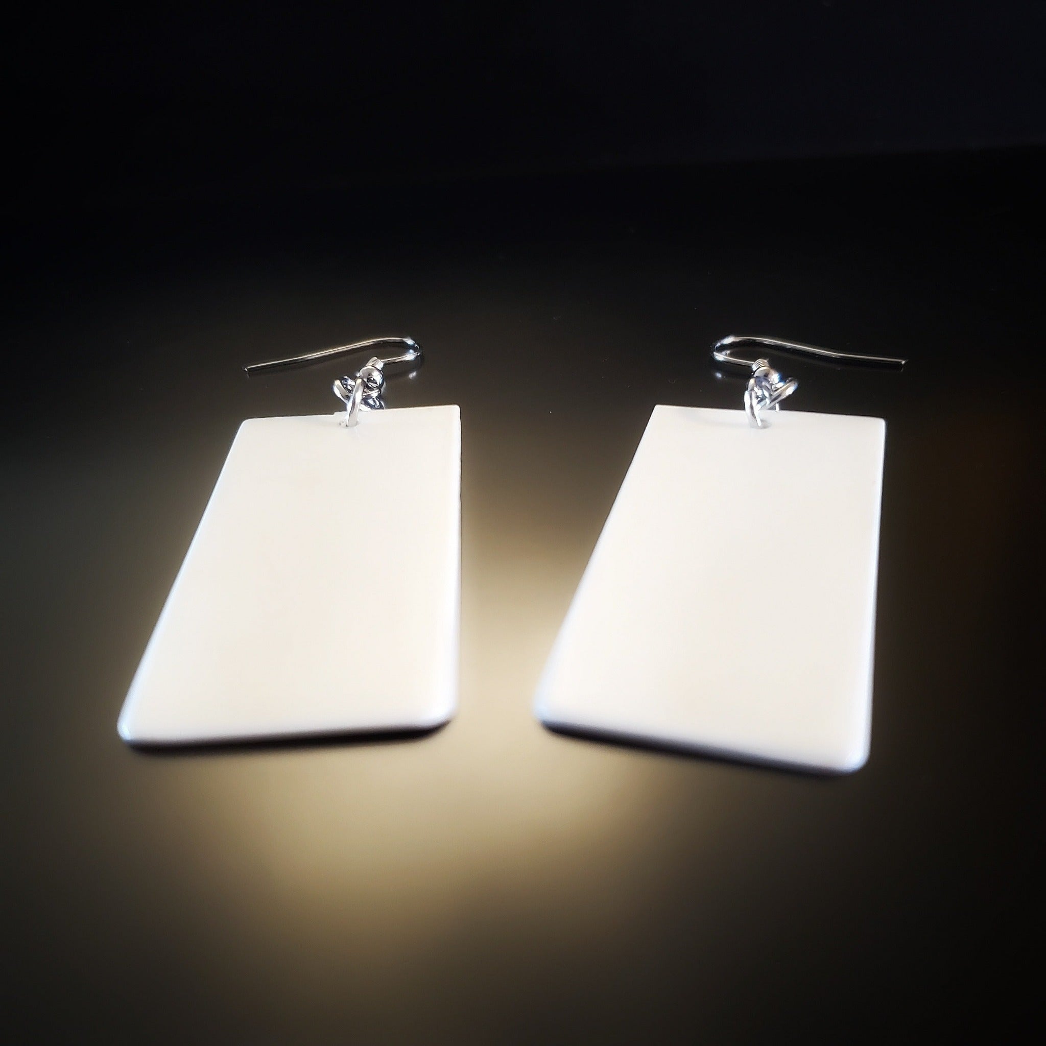 a pair of earrings made from upcycled ivory piano key toppers 