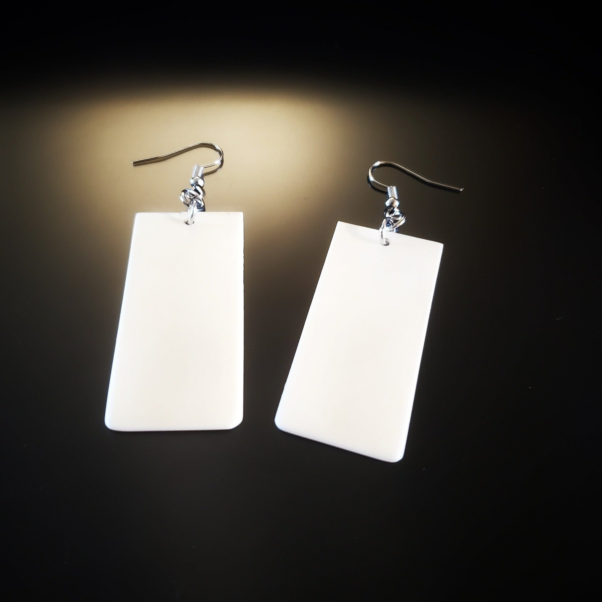 a pair of earrings made from upcycled ivory piano key toppers 
